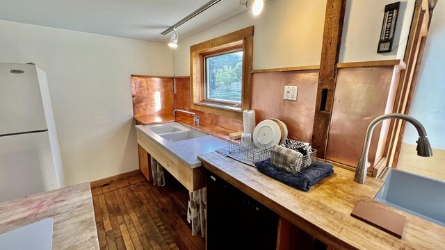 kitchen with brick wall, hardwood / wood-style floors, lofted ceiling with beams, black range with gas stovetop, and white refrigerator