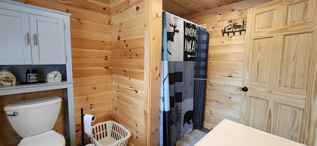 bathroom with toilet, a shower with shower curtain, and wooden walls