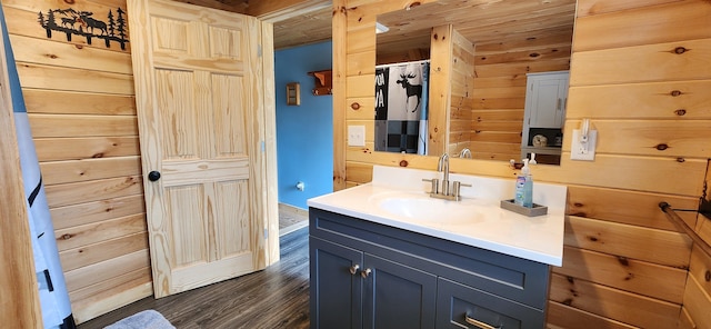 bathroom with hardwood / wood-style floors, walk in shower, wood walls, and vanity