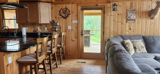 kitchen with a wealth of natural light, light hardwood / wood-style flooring, a breakfast bar, and wooden walls