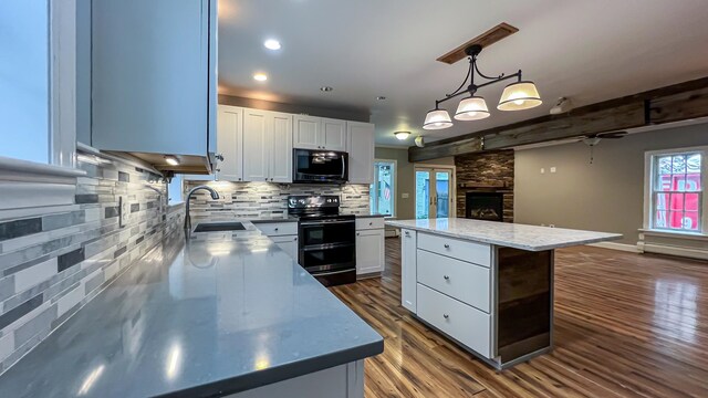 kitchen featuring hanging light fixtures, dark hardwood / wood-style flooring, white cabinetry, black appliances, and a kitchen island