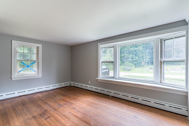 spare room featuring a baseboard heating unit and hardwood / wood-style flooring