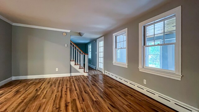 spare room with a baseboard heating unit, ornamental molding, and wood-type flooring