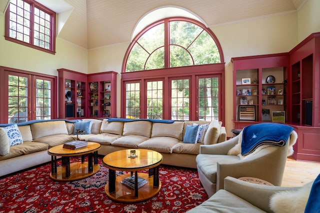 living area with wood finished floors, a high ceiling, and ornamental molding