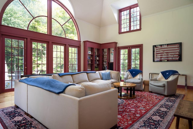 living room featuring plenty of natural light, french doors, a towering ceiling, and wood finished floors