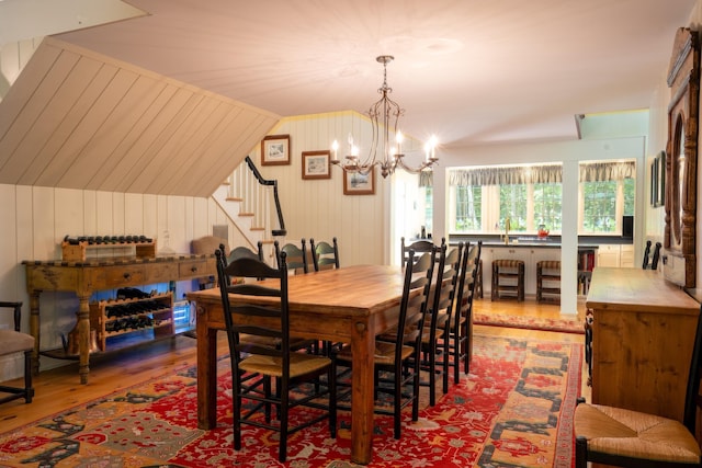 dining space featuring a chandelier, wood finished floors, stairs, and vaulted ceiling