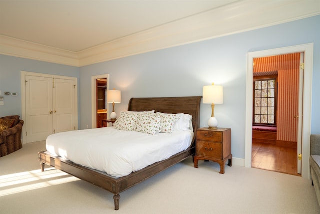 carpeted bedroom featuring a closet, connected bathroom, baseboards, and ornamental molding