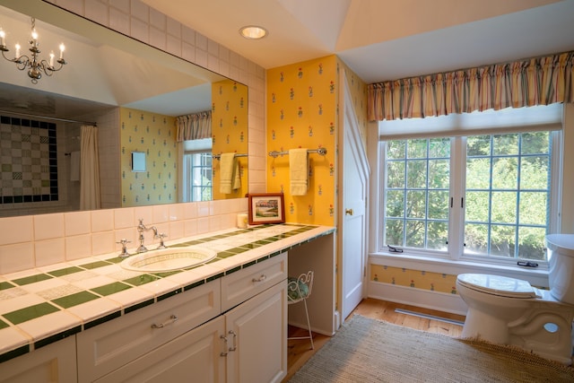 full bathroom with wallpapered walls, baseboards, toilet, wood finished floors, and vanity