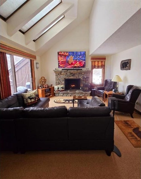 107 Blueberry Ledge Rdg Unit 45, Plymouth, VT 05056 - carpeted living area featuring beam ceiling, high vaulted ceiling, and a stone fireplace