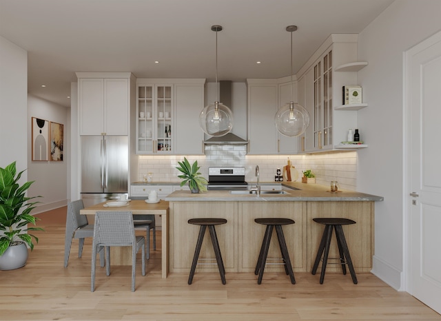 kitchen with a kitchen breakfast bar, wall chimney exhaust hood, stainless steel appliances, white cabinets, and hanging light fixtures