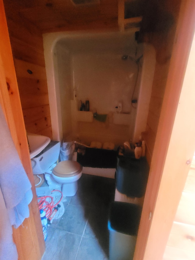 bathroom featuring wood walls, tile patterned floors, and toilet