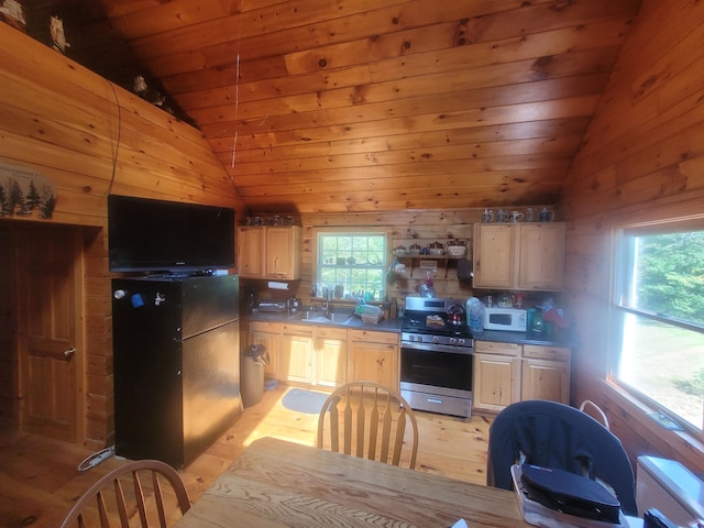 kitchen featuring light brown cabinetry, light hardwood / wood-style floors, black refrigerator, and stainless steel range oven