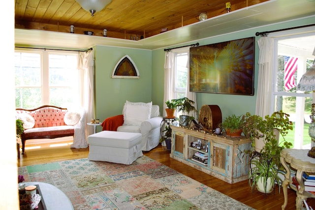 living area with a healthy amount of sunlight, wood-type flooring, and wooden ceiling