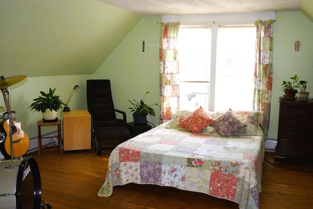 bedroom featuring a baseboard heating unit, lofted ceiling, and hardwood / wood-style floors