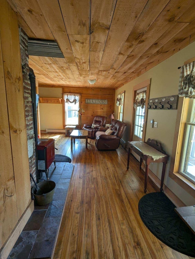 living room featuring wooden ceiling, hardwood / wood-style flooring, wood walls, and a wood stove