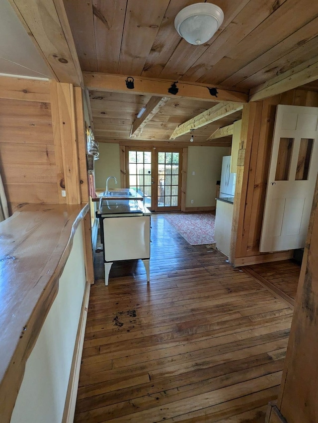 corridor featuring wooden walls, lofted ceiling with beams, french doors, wood ceiling, and dark wood-type flooring