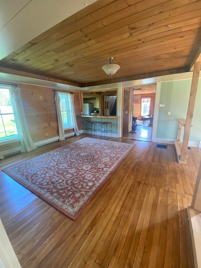 unfurnished living room with wood-type flooring, wooden ceiling, and a healthy amount of sunlight