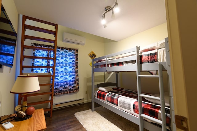 bedroom with baseboard heating, track lighting, a wall mounted AC, and wood finished floors