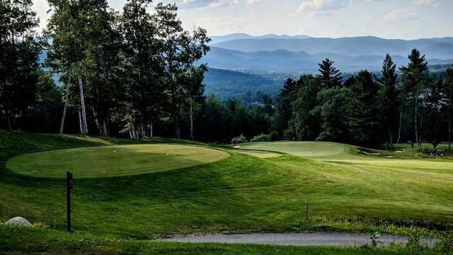 surrounding community with a mountain view, a lawn, and view of golf course