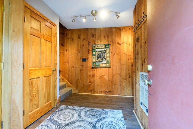 hall with stairway, wooden walls, rail lighting, and wood finished floors