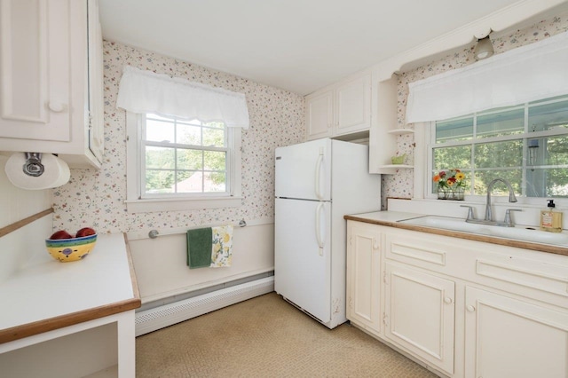 kitchen with a baseboard radiator, sink, white refrigerator, and white cabinetry