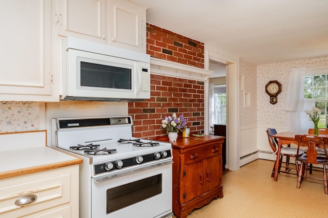 kitchen with white appliances, brick wall, and white cabinets