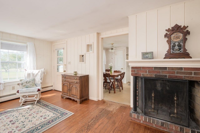 living area featuring a fireplace, a baseboard radiator, and light hardwood / wood-style floors