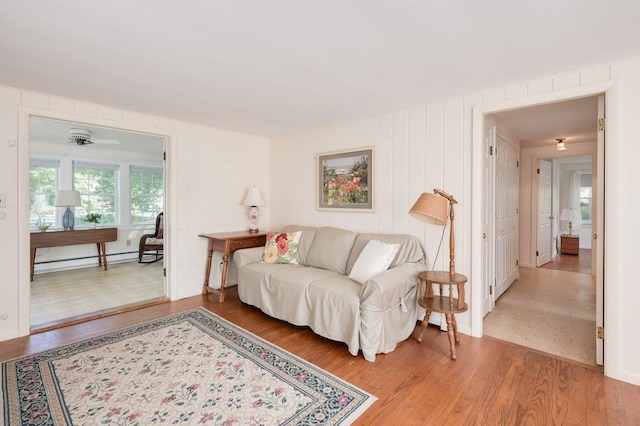 living room featuring a baseboard heating unit, wood-type flooring, and ceiling fan