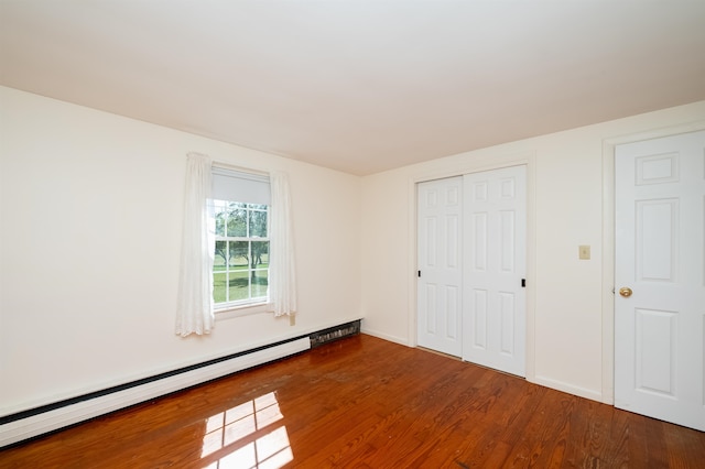 unfurnished room with hardwood / wood-style floors and a baseboard radiator