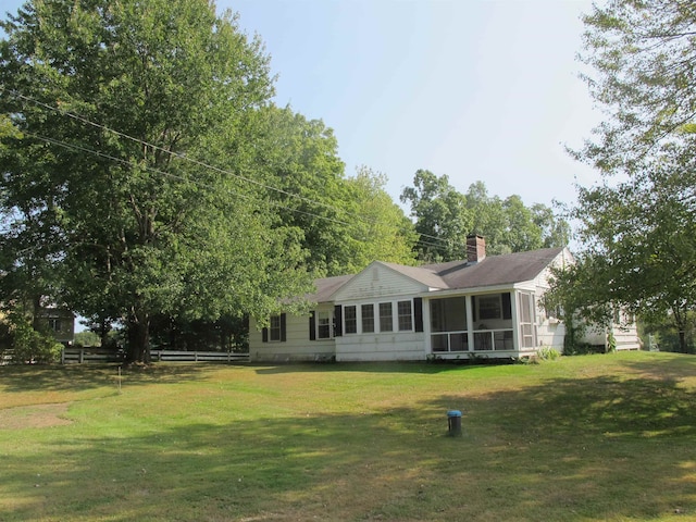 rear view of property featuring a lawn and a sunroom