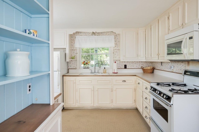 kitchen with sink, light carpet, white appliances, and white cabinetry