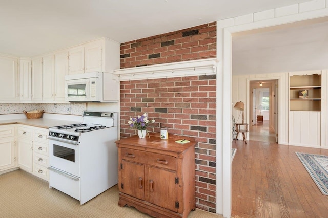 kitchen featuring light wood-type flooring, white appliances, white cabinetry, and brick wall