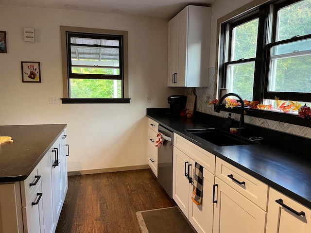 kitchen with dark countertops, a sink, and white cabinetry