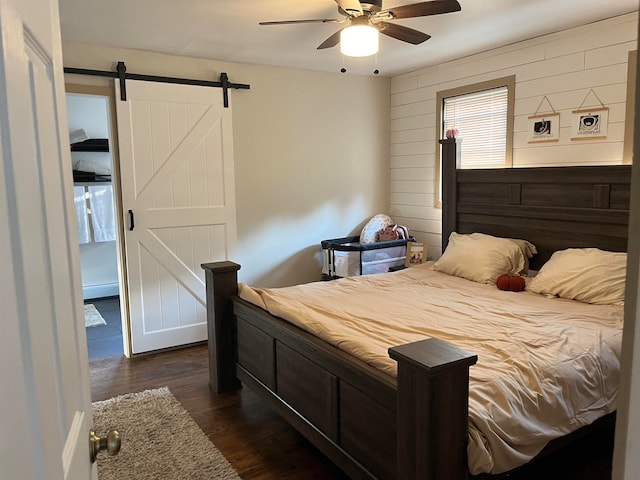 bedroom featuring dark wood-style floors, ceiling fan, and a barn door