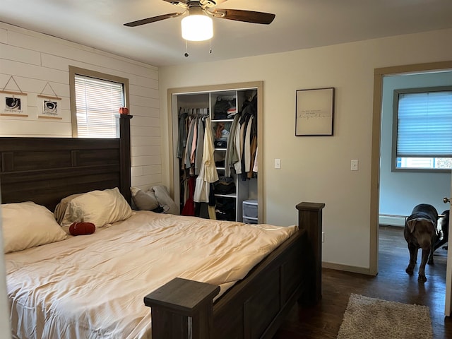 bedroom featuring dark wood-type flooring, a closet, multiple windows, and baseboards