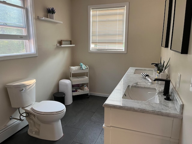 bathroom with double vanity, a sink, toilet, and baseboards