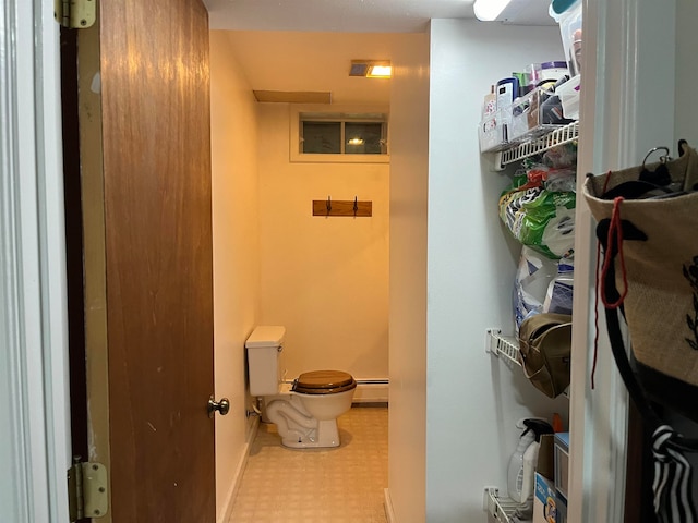 half bathroom featuring a baseboard radiator, baseboards, toilet, and tile patterned floors