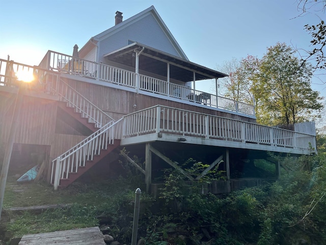 rear view of house with a chimney, stairway, and a deck