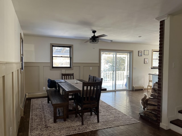 dining room with ceiling fan, a wainscoted wall, dark wood finished floors, and stairs