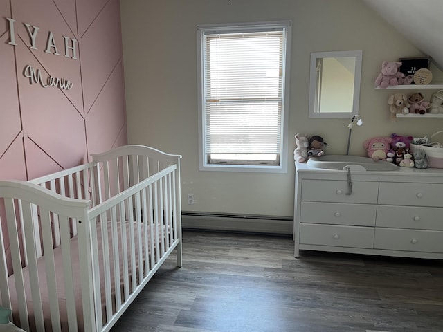 bedroom with vaulted ceiling, dark wood-type flooring, a crib, and baseboard heating