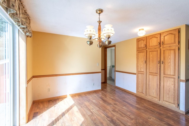6694 Vt Route 100, Troy, VT 05859 - unfurnished dining area featuring a notable chandelier, baseboards, visible vents, and wood finished floors
