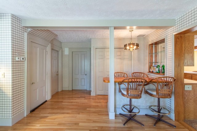 6694 Vt Route 100, Troy, VT 05859 - dining area featuring light wood-style flooring, a textured ceiling, and wallpapered walls