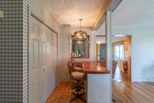 dining room with light hardwood / wood-style flooring, an inviting chandelier, and bar