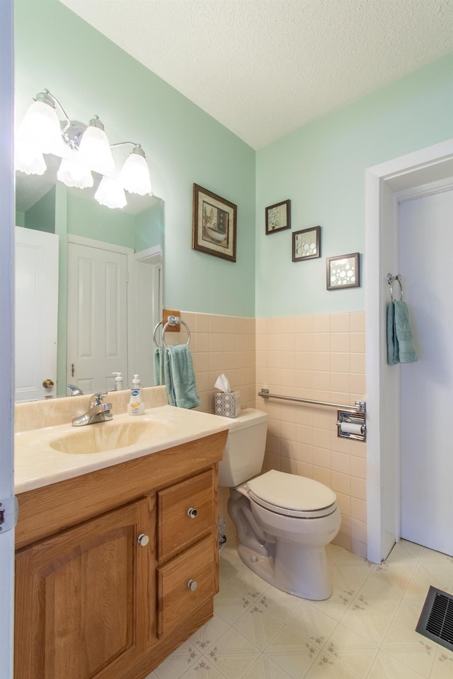 6694 Vt Route 100, Troy, VT 05859 - bathroom featuring vanity, toilet, visible vents, wainscoting, and tile walls