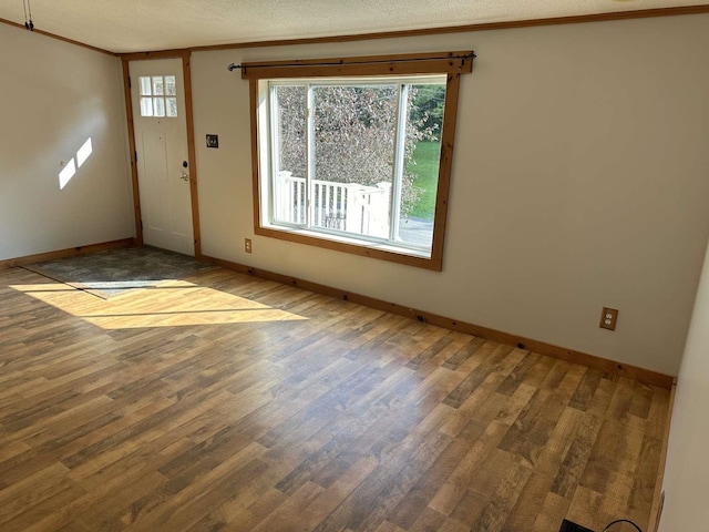 spare room with a textured ceiling, ornamental molding, and wood-type flooring