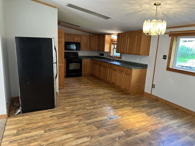 kitchen featuring light wood-type flooring, pendant lighting, a textured ceiling, black appliances, and sink