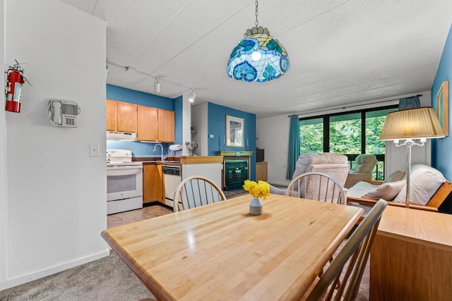 carpeted dining room with a textured ceiling, floor to ceiling windows, sink, and track lighting