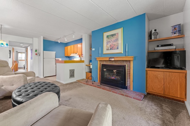 living room featuring a textured ceiling, light colored carpet, a brick fireplace, and track lighting