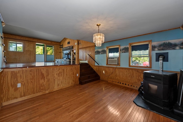 interior space featuring a wealth of natural light, wood walls, a wood stove, and light hardwood / wood-style floors