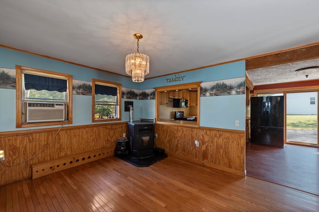 kitchen with cooling unit, hanging light fixtures, hardwood / wood-style flooring, a notable chandelier, and black appliances